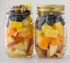 two mason jars filled with fruit and nuts, one containing blueberries, the other mixed