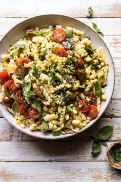 a white bowl filled with pasta salad on top of a wooden table