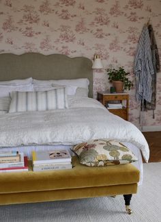 a bed with pillows and blankets on it next to a wallpapered bedroom area