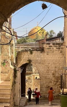 two women walking down an alley way in the old city with stone walls and arched doorways