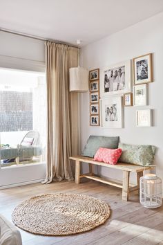 a living room with pictures on the wall and a bench in front of a window