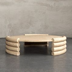 a coffee table made out of wooden logs sitting on top of a cement floor next to a wall