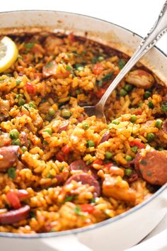 a large pot filled with rice and sausage next to a lemon slice on the side