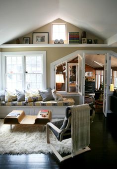 a living room filled with lots of furniture next to two windows and bookshelves