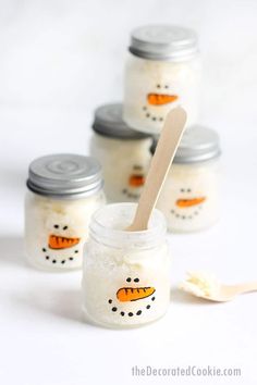 four jars with snowmen painted on them and one has a wooden spoon in it