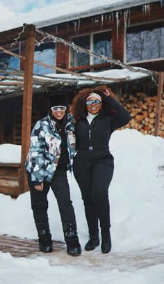 two people standing in the snow with skis on their heads and one person wearing goggles