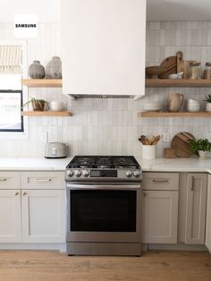 a stove top oven sitting inside of a kitchen next to white cabinets and open shelves