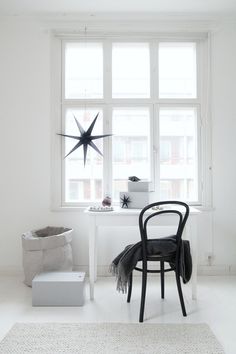 a white room with a chair, table and star decoration on the window sill