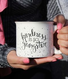 a person holding a coffee mug with writing on the side and pink nail polishes