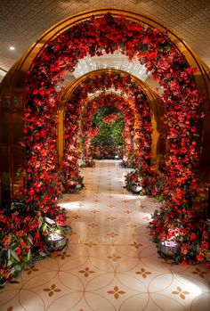 an archway decorated with red flowers and potted plants