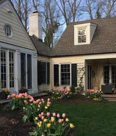 a house with tulips and other flowers in the front yard