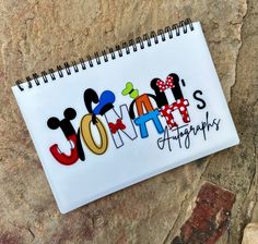 a spiral notebook with the word journal written in colorful letters on it and mickey mouse