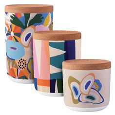 three colorful ceramic containers with cork lids and cork tops, each decorated with an abstract floral design