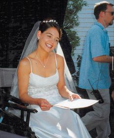 a woman sitting in a chair holding a piece of paper and smiling at the camera