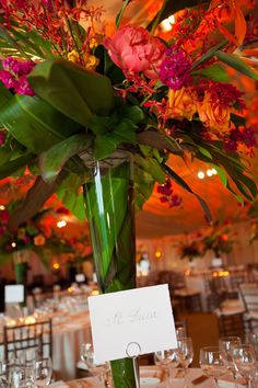 a vase filled with flowers on top of a table covered in white linens and place cards