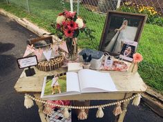 an open book sitting on top of a wooden table next to a vase filled with flowers