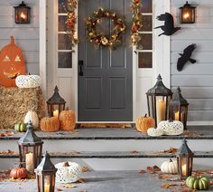 a front porch decorated for halloween with pumpkins, hay bales and lantern lights