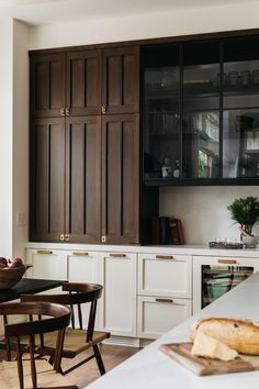 a kitchen filled with lots of wooden cabinets and counter top space next to a dining room table