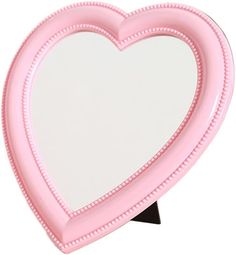 a pink heart shaped mirror sitting on top of a table