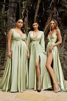 three women in long dresses standing next to each other with their legs slited up