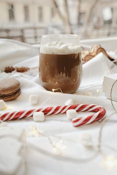 a hot chocolate drink with marshmallows and candy cane on a white table cloth