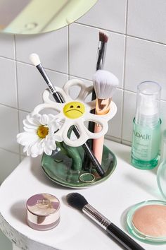 various makeup products are arranged on a small table in front of a mirror and tiled wall