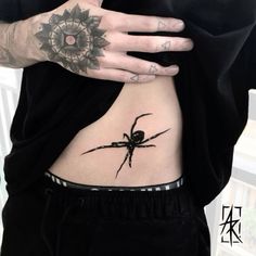 a spider tattoo on the side of a woman's stomach