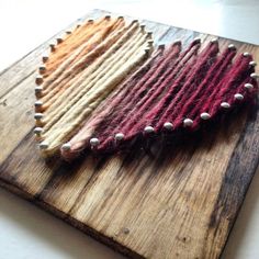 three different colored pieces of yarn on a wooden cutting board with white bead trim