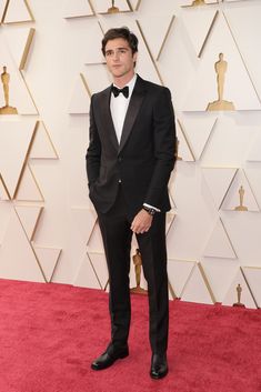 a man in a tuxedo standing on a red carpet