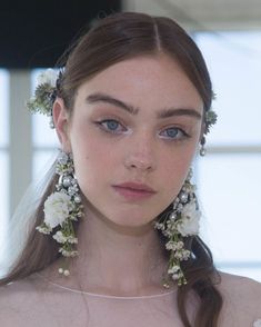 a woman with flowers in her hair wearing earrings and a veil on her head,