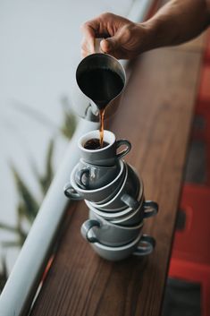 a person pouring coffee into a stack of cups