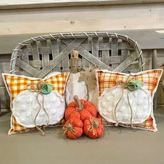 three pumpkins are sitting in front of two decorative pillows