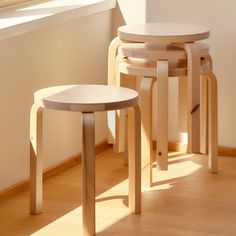 three stools sitting next to each other on a wooden floor in front of a window