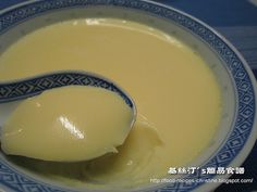 a spoon full of yellow liquid in a blue and white bowl