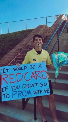 a man holding a sign that says it would be a redcard if you didn't go to prom with me