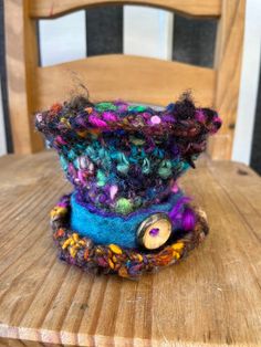 This is a mini version of my crochet wonky top hat design! Crocheted with my magic scrap yarn which makes it super one off! Finished with a hand felted band and hand crafted wooden button.  Handspun, hand dyed, pure wool. Super luxurious. A true one of a kind piece of wearable fiber art.  Approx 10cm tall. No attachments. Best worn with a hat pin or some cleverly placed hair grips 🤓 Pattern and design original to The Magician's Wardrobe. A one of a kind piece and is built to last. It can withst Handmade Multicolor Crochet Hat Whimsical Style, Hand Knitted Multicolor Crafts, Handmade Multicolor Whimsical Crochet Hat, Whimsical Handmade Multicolor Crochet Hat, Handmade Multicolor Crochet Hat, Whimsical Multicolor Handmade Crochet Hat, Whimsical Multicolor Mini Hats For Festivals, Handmade Yarn Bohemian Mini Hats, Handmade Bohemian Mini Hats In Yarn