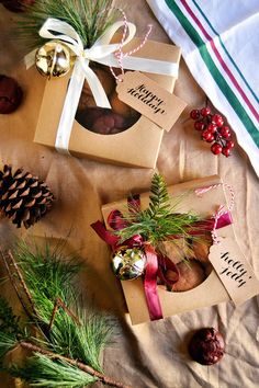 three christmas gifts wrapped in brown paper and tied with red ribbon, pine cones, evergreen needles, and other holiday decorations