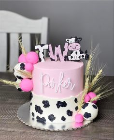 a two tiered cake decorated with black and white polka dots, pink frosting, and letters