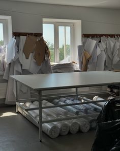 a room filled with lots of white sheets and clothes hanging on the wall next to windows