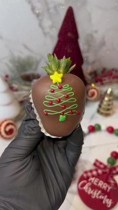 a hand holding up a chocolate covered apple with christmas decorations on it's head