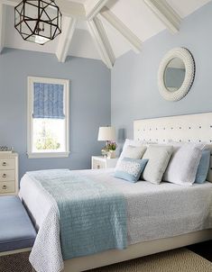 a bedroom with blue walls, white bedding and a chandelier hanging from the ceiling