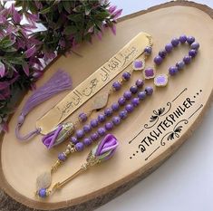 a wooden plaque with some purple beads on it and flowers in the backround