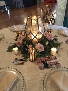 a table topped with candles and flowers on top of a white cloth covered tablecloth