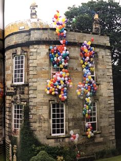 an old building with balloons attached to the windows and in front of it is a spiral staircase