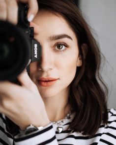 a woman is holding up a camera to take a photo with her eyes wide open