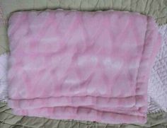 two pink and white blankets laying on top of each other