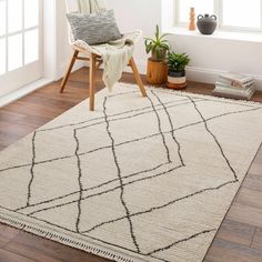 a white rug with black lines on it in front of a chair and potted plant