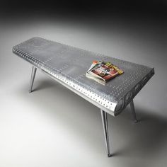 a metal table with a magazine on it's top and two legs that have holes in the middle