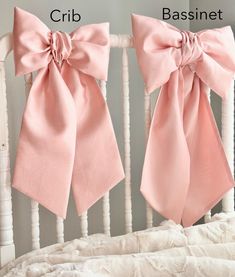 two pink bows hanging from the back of a crib