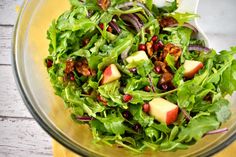 a salad in a bowl with apples and cranberries on the side is ready to be eaten